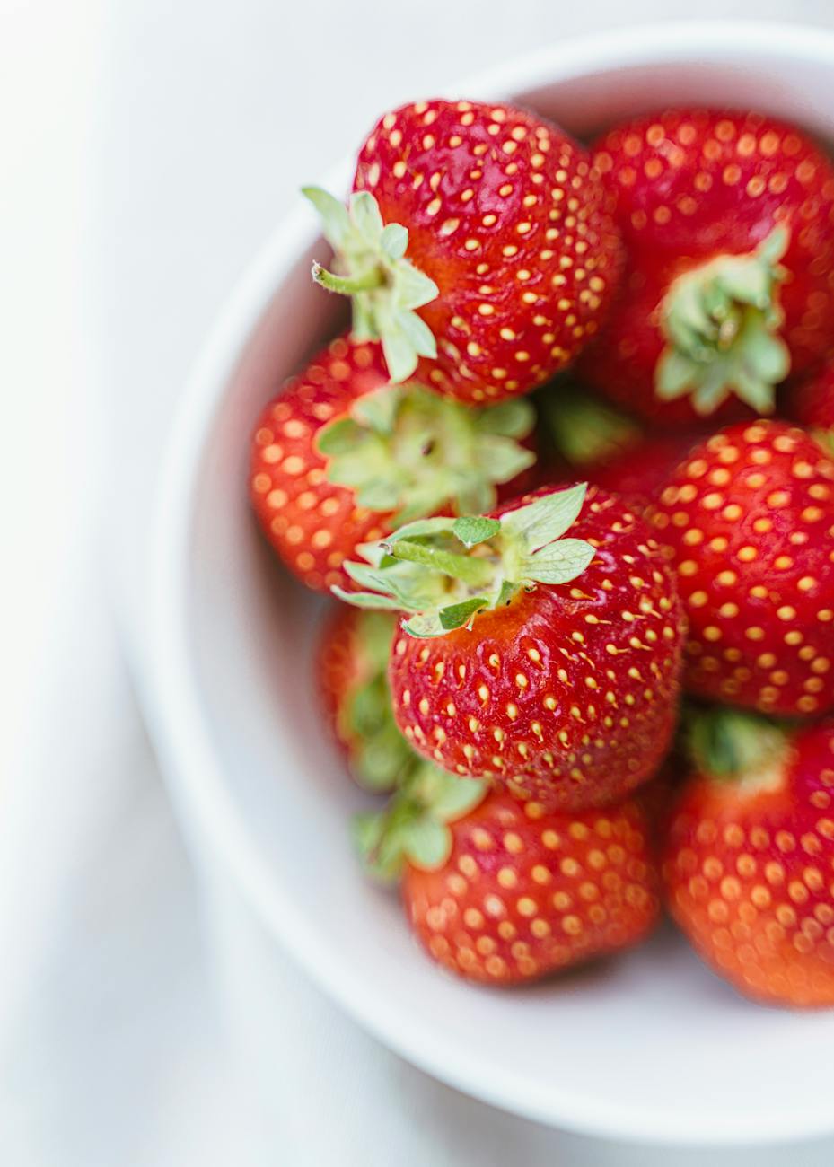 ripe strawberries in white plate on table